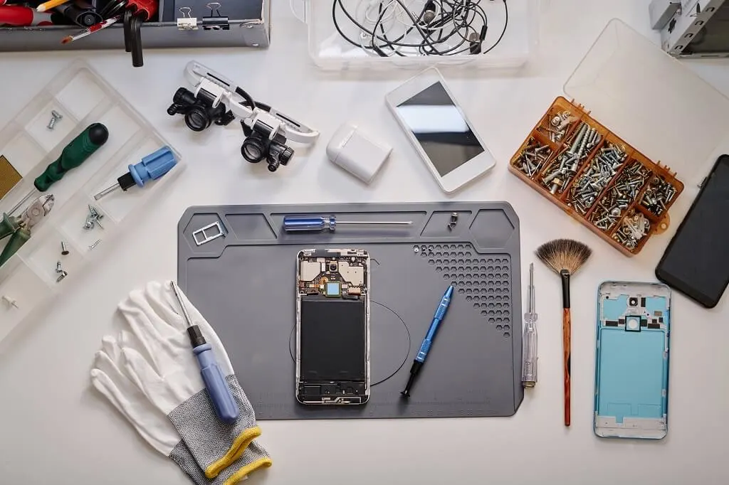 Smartphone repair workbench with tools and phone parts for professional mobile device servicing and maintenance