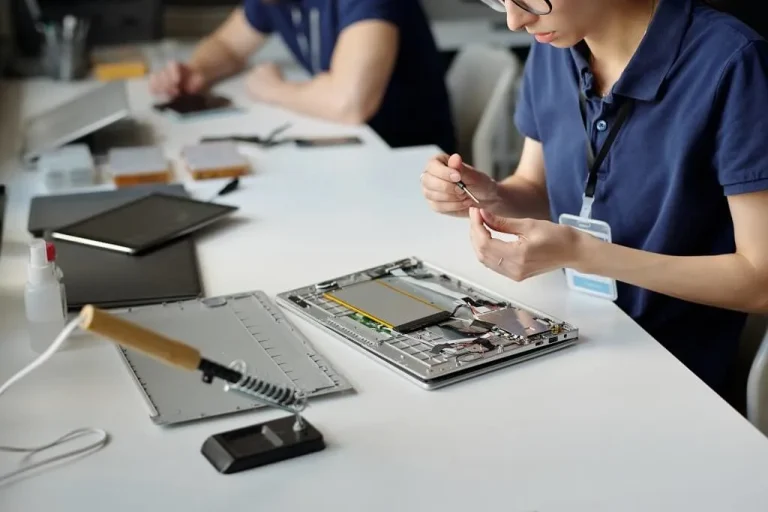 Hands of female technician repairing a Lenovo laptop in Singapore using professional tools at a repair workstation.