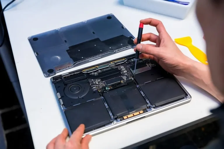 MacBook screen repair in Singapore with a screwdriver on a white worktable.