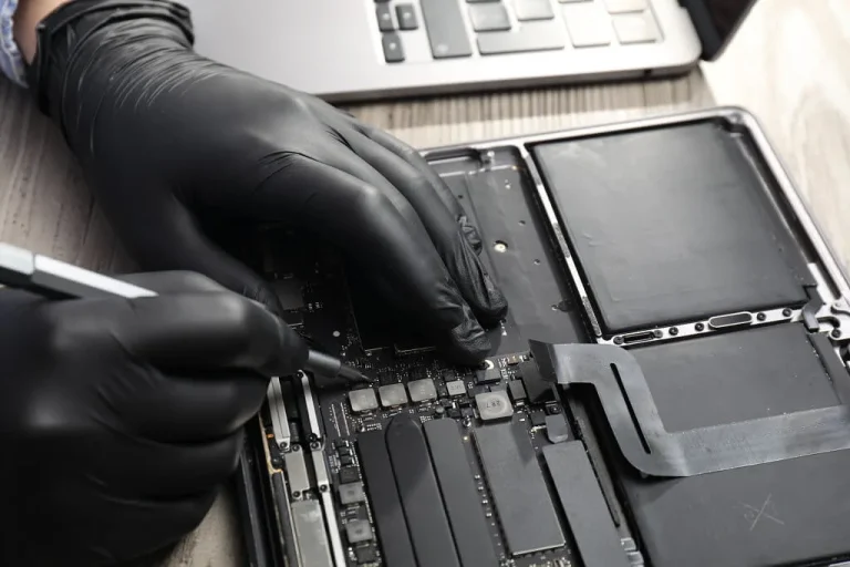 Technician repairing MacBook internal components with precision tools in Singapore.
