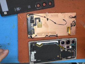 Samsung Galaxy S25 Ultra opened on a repair mat with removed components placed beside the phone.