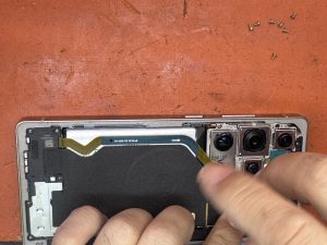 Close-up of a technician working on the internal components of an opened Samsung Galaxy S25 Ultra.