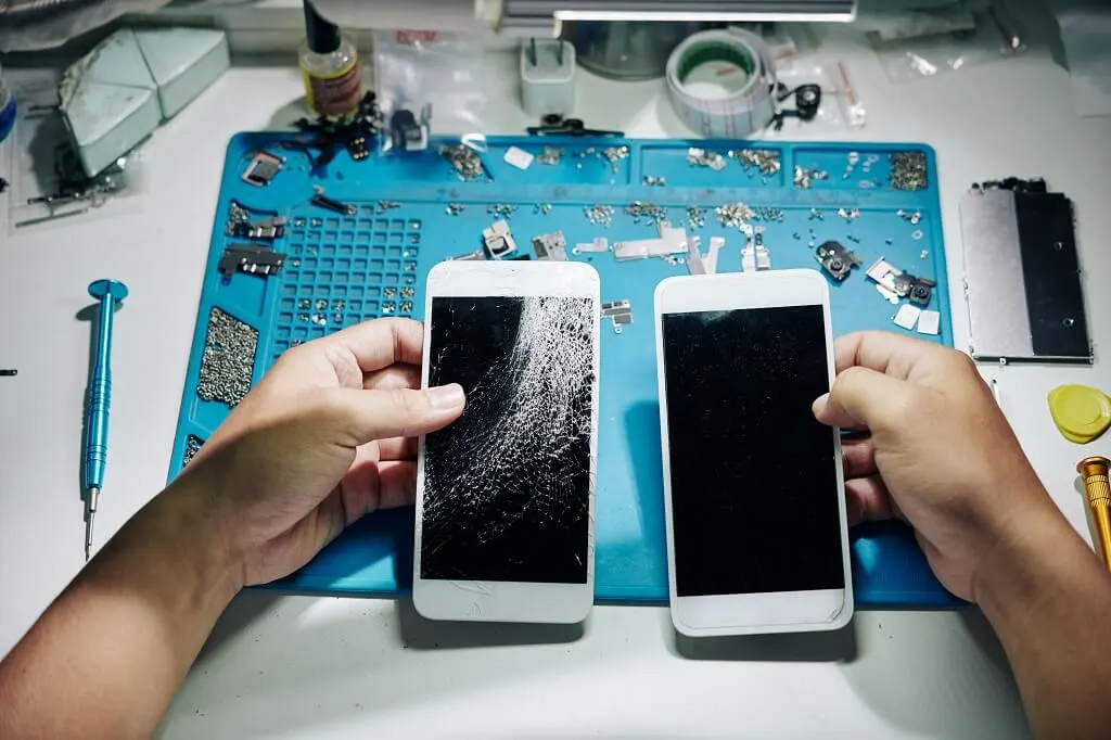 Technician repairing a cracked Huawei phone screen with tools on a work desk.